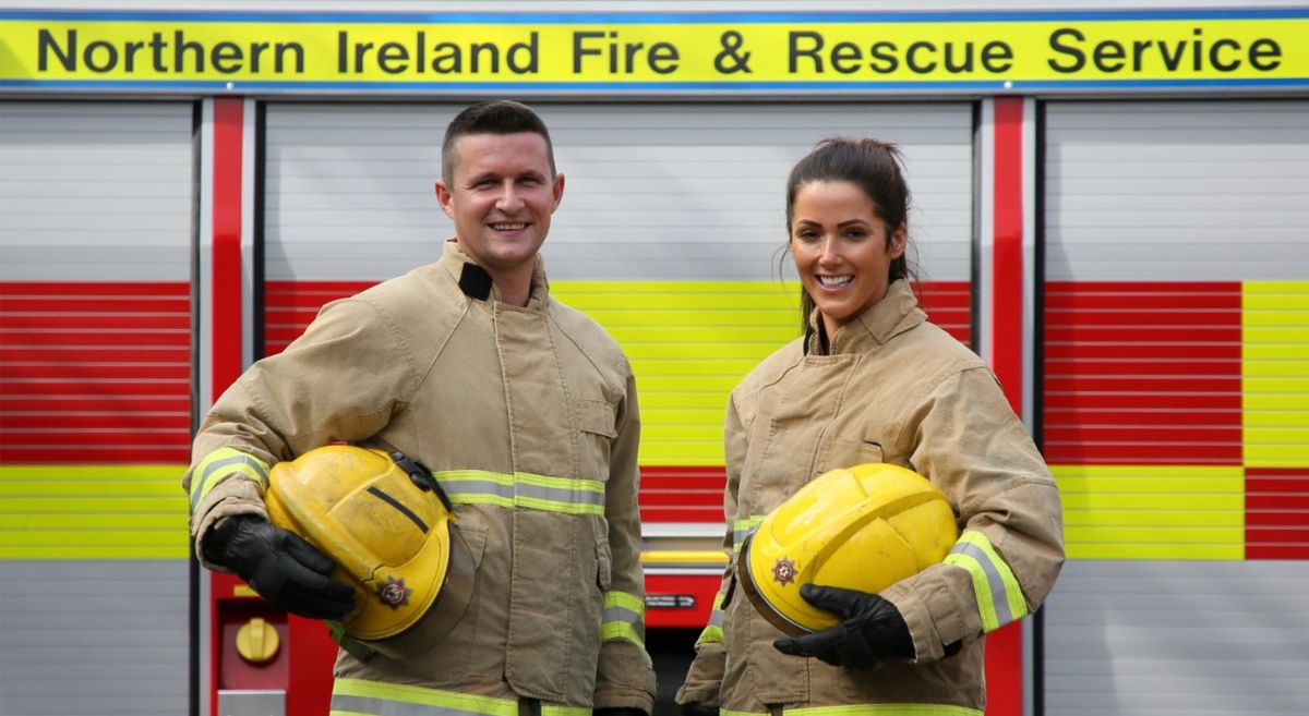 A male and a female fire rescue officers in uniform in front of a fire engine